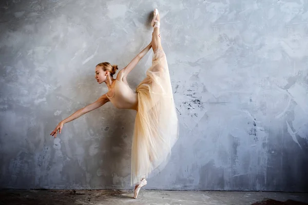 Молодая балерина в золотом танцевальном костюме позирует в лофт-студии — стоковое фото