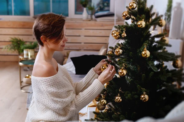 Giovane donna sta decorando l'albero di Natale creando l'atmosfera di festa — Foto Stock
