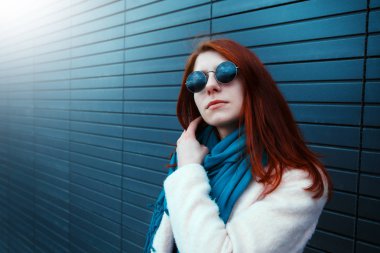 Hipster redhaired kız şık güneş gözlüğü siyah duvar sokak önünde poz
