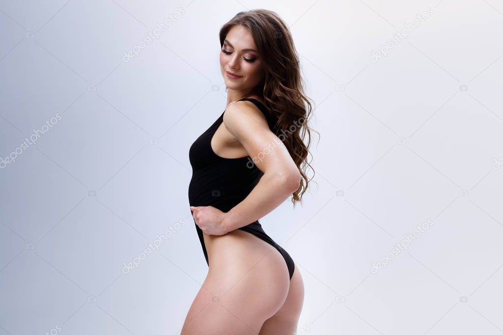 Long haired fitness model in a sexy suit is posing on a neutral background