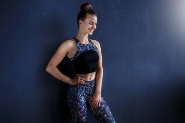 Güzel fitness modeli karanlık eğitim elbiseli karanlık duvar önünde poz