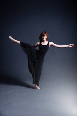 Siyah bir elbise dansçı karanlık stüdyoda dans ediyor