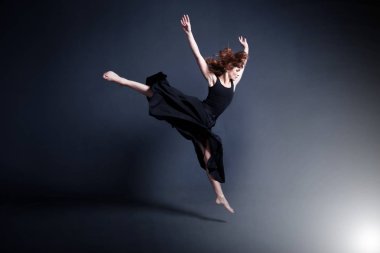 Siyah bir elbise dansçı karanlık stüdyoda dans ediyor
