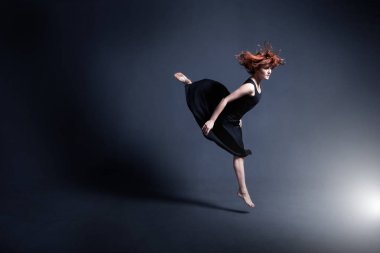 Siyah bir elbise dansçı karanlık stüdyoda dans ediyor