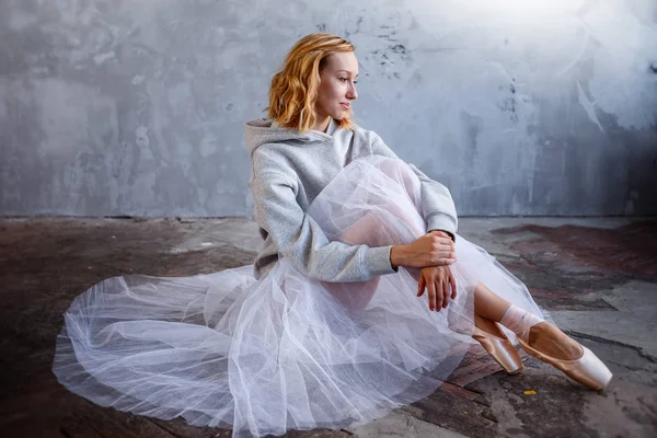 Junge und schlanke Balletttänzerin posiert in einem stilvollen Studio mit großen Fenstern — Stockfoto