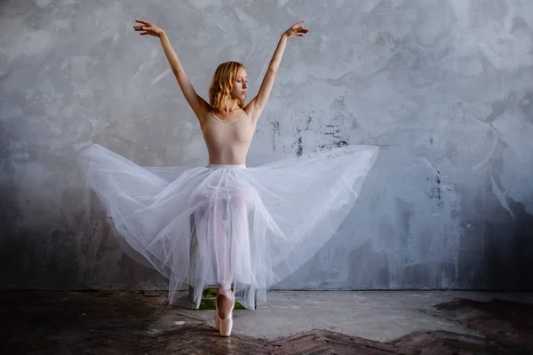 Ung och smal balettdansös poserar i en elegant studio med stora fönster — Stockfoto