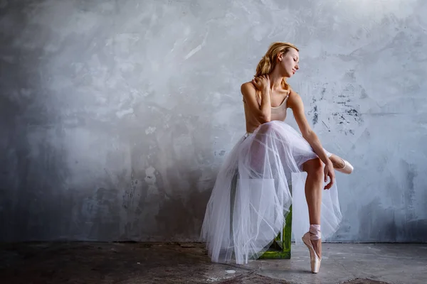 Junge und schlanke Balletttänzerin posiert in einem stilvollen Studio mit großen Fenstern — Stockfoto