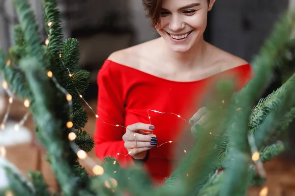 Giovane donna sta decorando l'albero di Natale nel bellissimo interno — Foto Stock