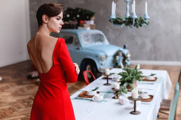 Mladá dívka v červených šatech je Pózování na vánoční decored interiér — Stock fotografie