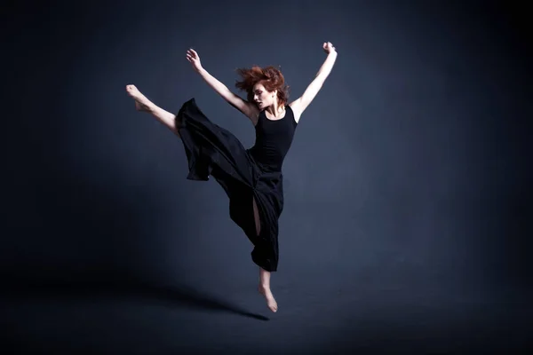 Dancer in a black dress is dancing in the dark studio Royalty Free Stock Images