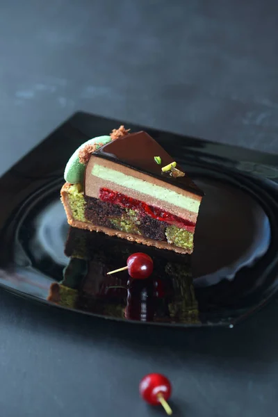 Stück zeitgenössischer Moussekuchen aus Schokolade, Kirsche und Pistazien — Stockfoto