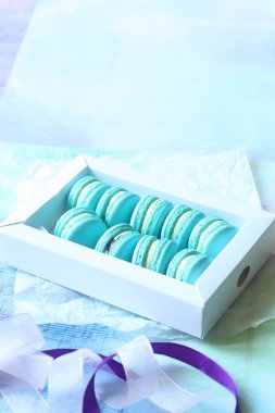 Krem peynir ve yaban mersini girmede, ışık mavi zemin üzerine mavi Macarons. 