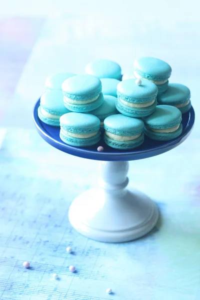 Macarons azuis com creme de queijo e enchimento de mirtilo, no fundo azul claro . — Fotografia de Stock
