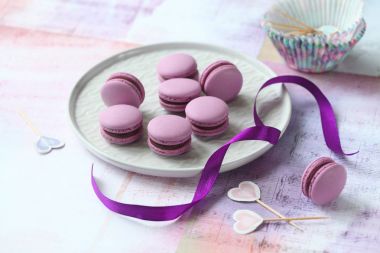 Mor Macarons çikolata Siyah frenk üzümü doldurma ile ışık arka plan üzerinde gri plaka üzerinde.