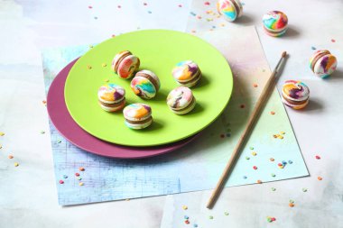 Gökkuşağı Macarons ile sütlü çikolata Dolum, ışık mavi zemin üzerine yeşil plaka üzerinde.