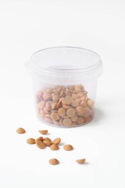 Beyaz arka planda şeffaf bir kovada damla damla Belçika Karamel Çikolatası.