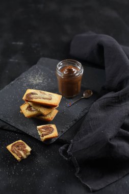 Mini Financier Pastaları ve biraz çikolata ezmesi, kara tahtada, siyah arka planda..