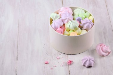 Beyaz bir kutuda, açık ahşap arka planda renkli kurabiyeler..