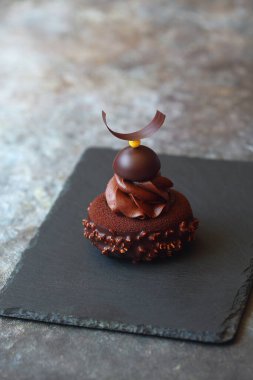 Çağdaş çikolatalı mini kremalı kremalı ve çikolatalı kadife sprey ve çikolata kaplı mango reçelli, çırpılmış çikolatalı ganache ile süslenmiş,.