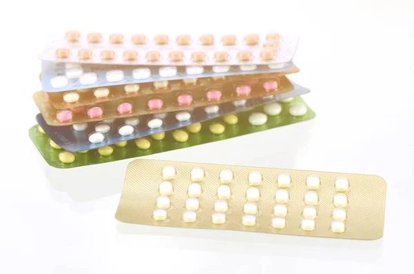 Мини-таблетки с оральными противозачаточными таблетками на заднем плане в теплом свете — стоковое фото