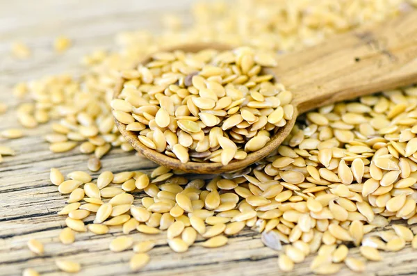 Spoonful of golden flax seed on wood background. — Stock Photo, Image