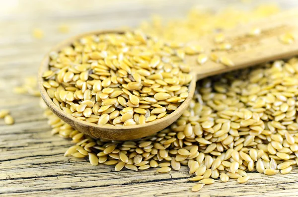 Spoonful of golden flax seed on wood background. — Stock Photo, Image