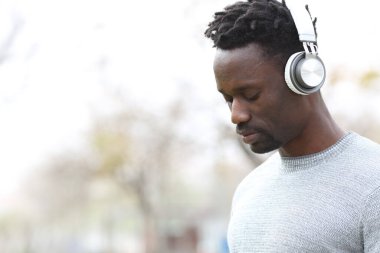 Kulaklık takmış, müzik dinleyen düşünceli siyah bir adam.