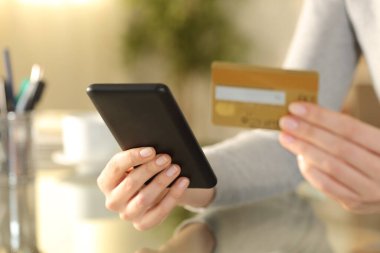 Akıllı telefon ve kredi kartını evdeki bir masada tutan kadınların ellerini kapat.