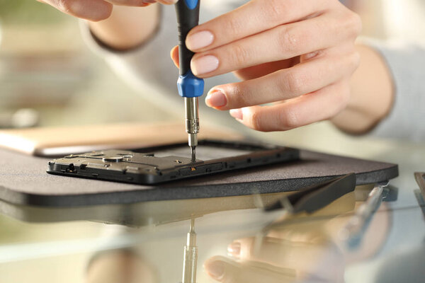 Woman using screwdriver on a smart phone on a desk