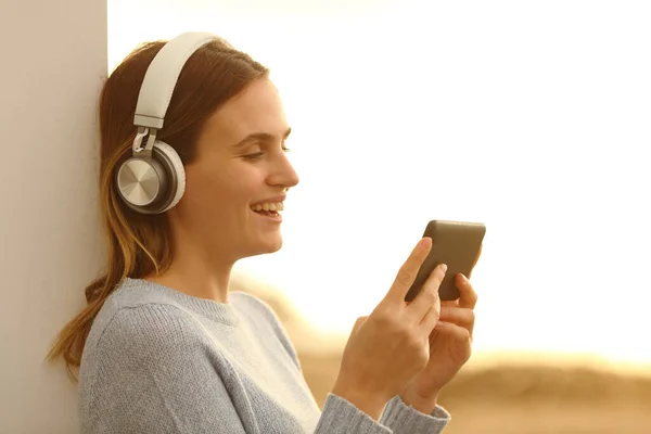 Telefondaki Kulaklıkla Medyayı Izleyen Mutlu Kadın — Stok fotoğraf