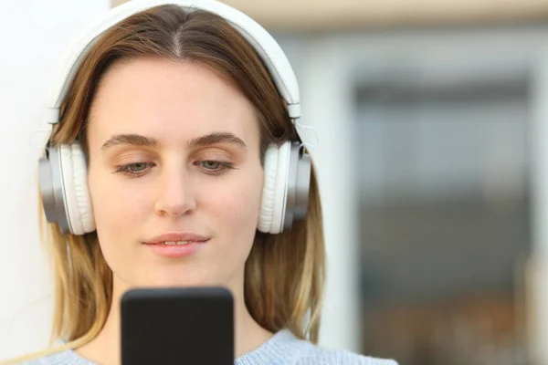一个女人的正面肖像 她带着耳机 在阳台上用智能手机听音乐 — 图库照片