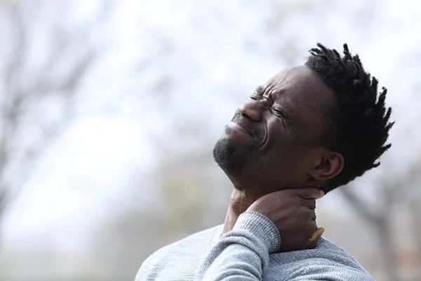 Black man suffering neck ache complaining outdoors