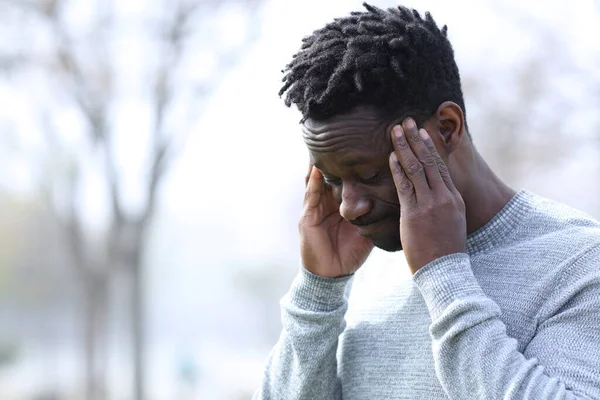 Zenci adam dışarıda tapınağa dokunurken migren ağrısı çekiyor.