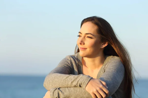 自信的单身女子坐在沙滩上观看日落 — 图库照片