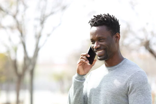 快乐的黑人男人在智能手机上一边看一边在公园里 — 图库照片