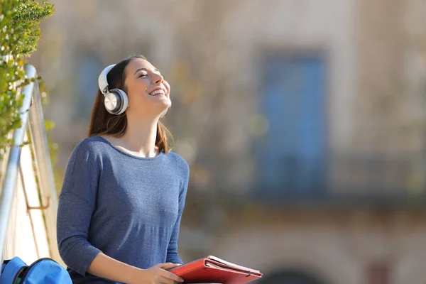 幸せな学生は 大学のキャンパスで屋外に座ってヘッドフォンを着用して音楽を聴く瞑想 — ストック写真