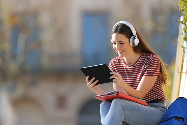 ヘッドフォンとタブレットの学習を持つ幸せな学生は 大学のキャンパスで屋外に座って — ストック写真