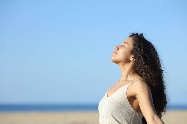 Side view portrait of a relaxed latin girl breathing deeply fresh air on the beach a sunny day