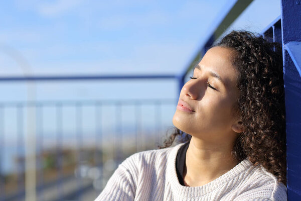 Relaxed latina girl sitting on stairs leaning in a railing heating in a sunny day