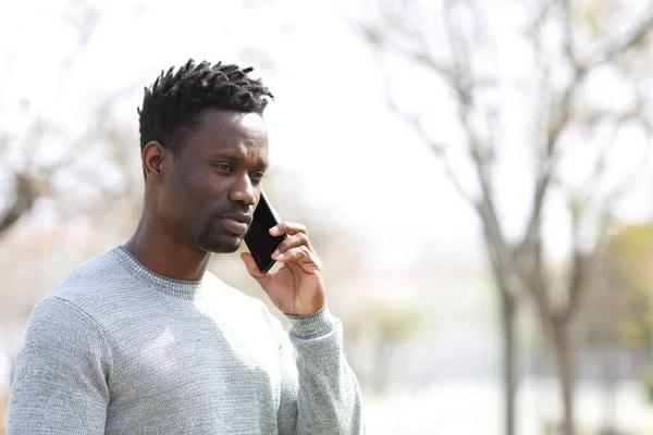 一个严肃的黑人男子在停车场用智能手机打电话 — 图库照片