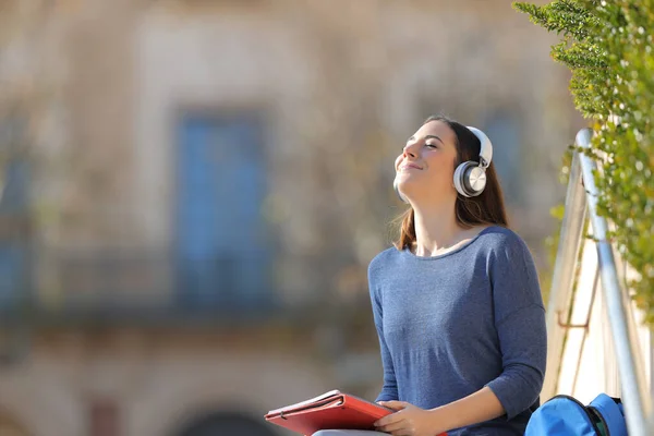 大学のキャンパスの屋外に座ってヘッドフォンを着用して音楽を聴く学生瞑想 — ストック写真