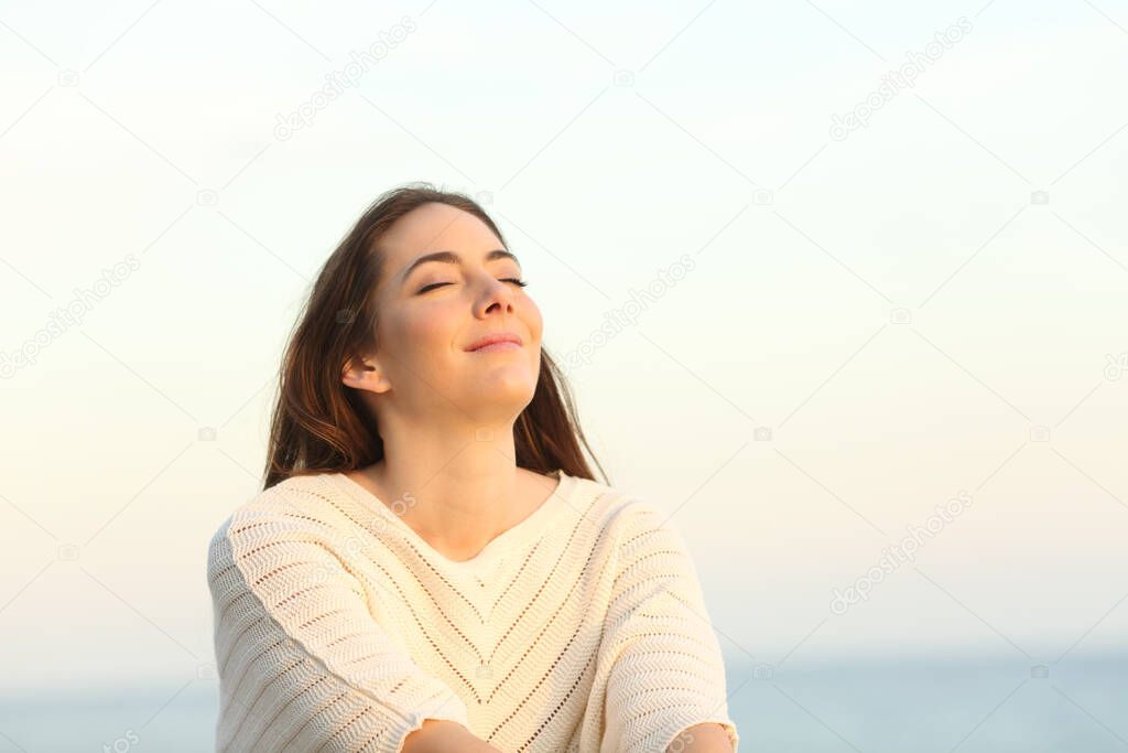 Relaxed woman breaths fresh air sitting on the beach