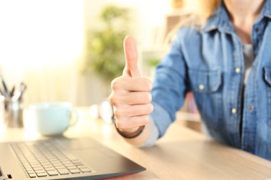 Öğrenci kızın el hareketleriyle evdeki bir masada baş parmak hareketi yapması.