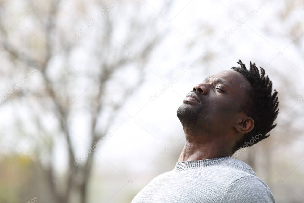 Black man breathing deep fresh air outdoors in winter in a park