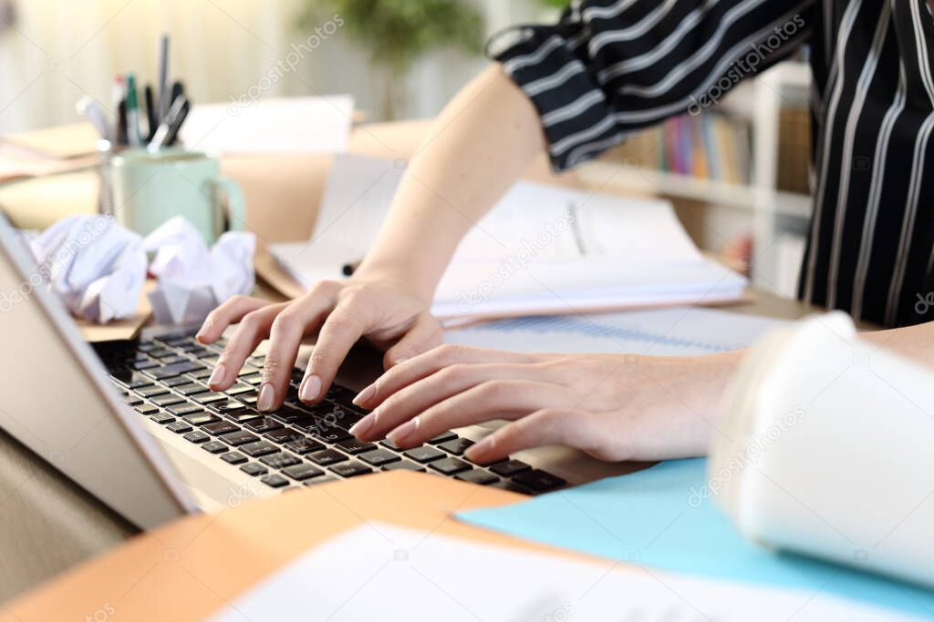 Messy entrepreneur hands working on laptop on a desk