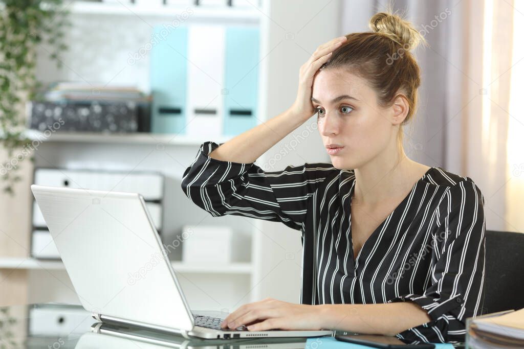 Surprised woman making mistake online working on laptop sitting on a desk at home office