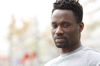 Kendine güvenen siyah bir adam parkta kameraya bakıyor.