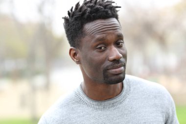 Şüpheli siyahi bir adam parkın dışında kameraya bakıyor.