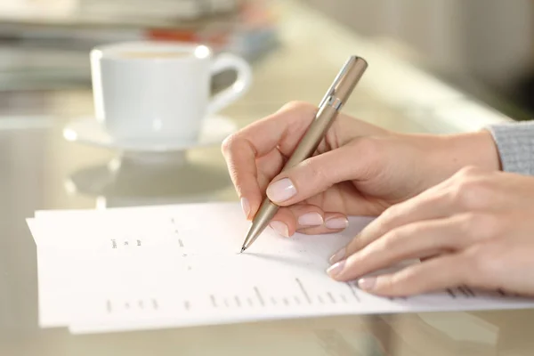 Close up side view of woman hand filling out checkbox form on a desk at home