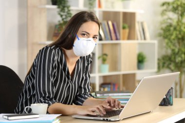 Covid-19 hapisanesinde koruyucu maske takan, laptop görünümlü bir kamera takan bir tele-işçi, merkezdeki bir masada oturuyor.
